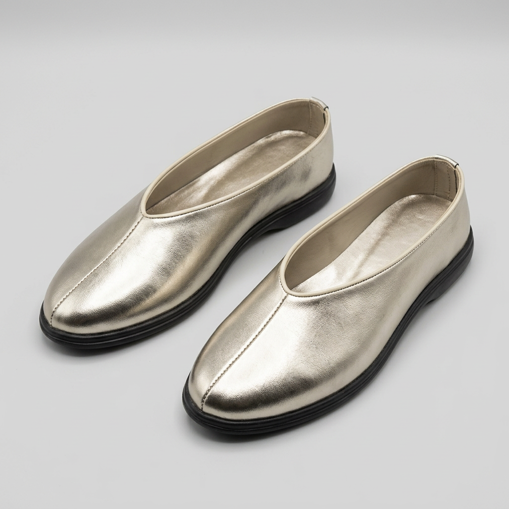 Matching pair of champagne-silver metallic slip-on shoes on a studio background